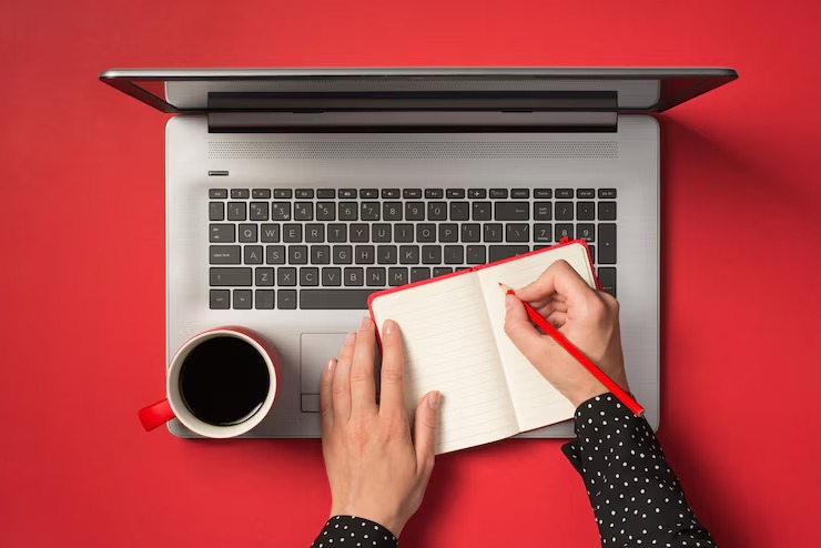 imgi_32_first-person-top-view-photo-female-hands-writing-with-red-pencil-red-notepad-cup-coffee-laptop-isolated-red-background_352249-5319